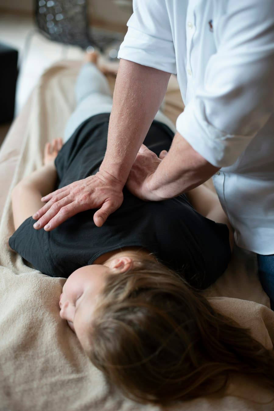 Fisioterapeuta realizando terapia manual nas costas de uma paciente deitada